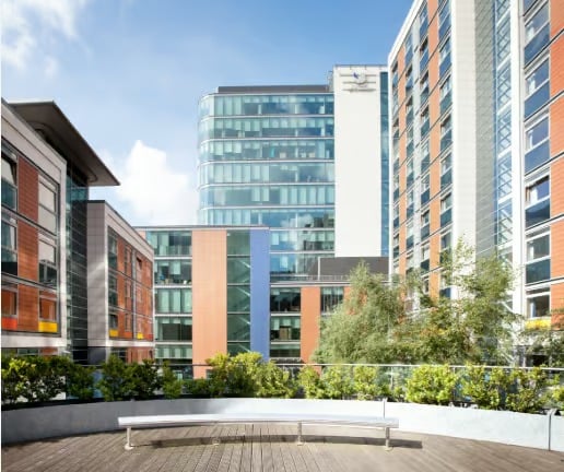 Bench on wooden deck with modern buildings exterior at The Paragon in London Student Accommodation