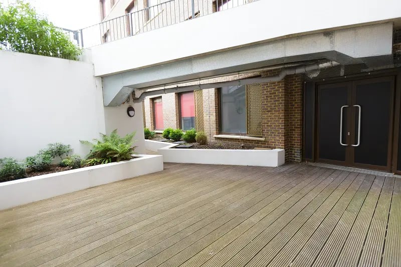 Decking area with planters and building entrance exterior at AXO New Cross in London Student Accommodation