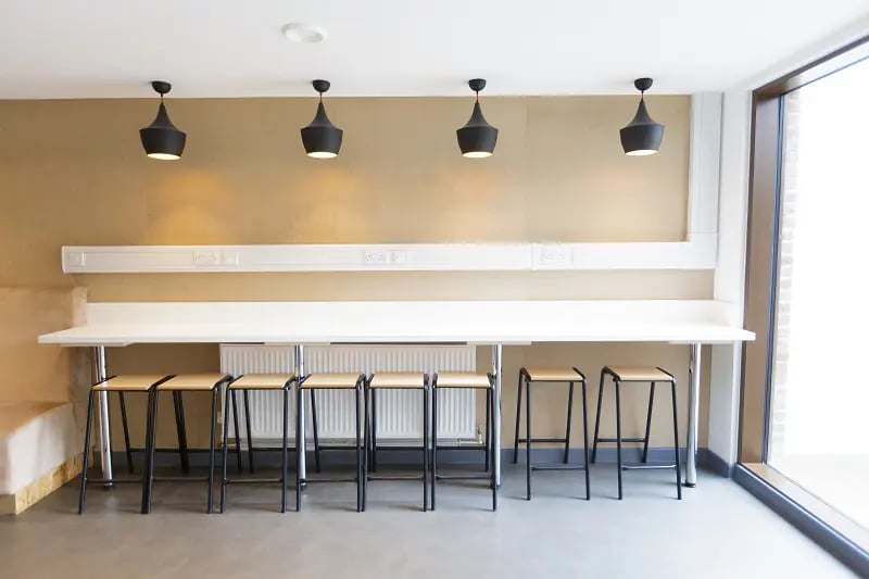 Long table with stools and pendant lights communal area at AXO New Cross in London Student Accommodation