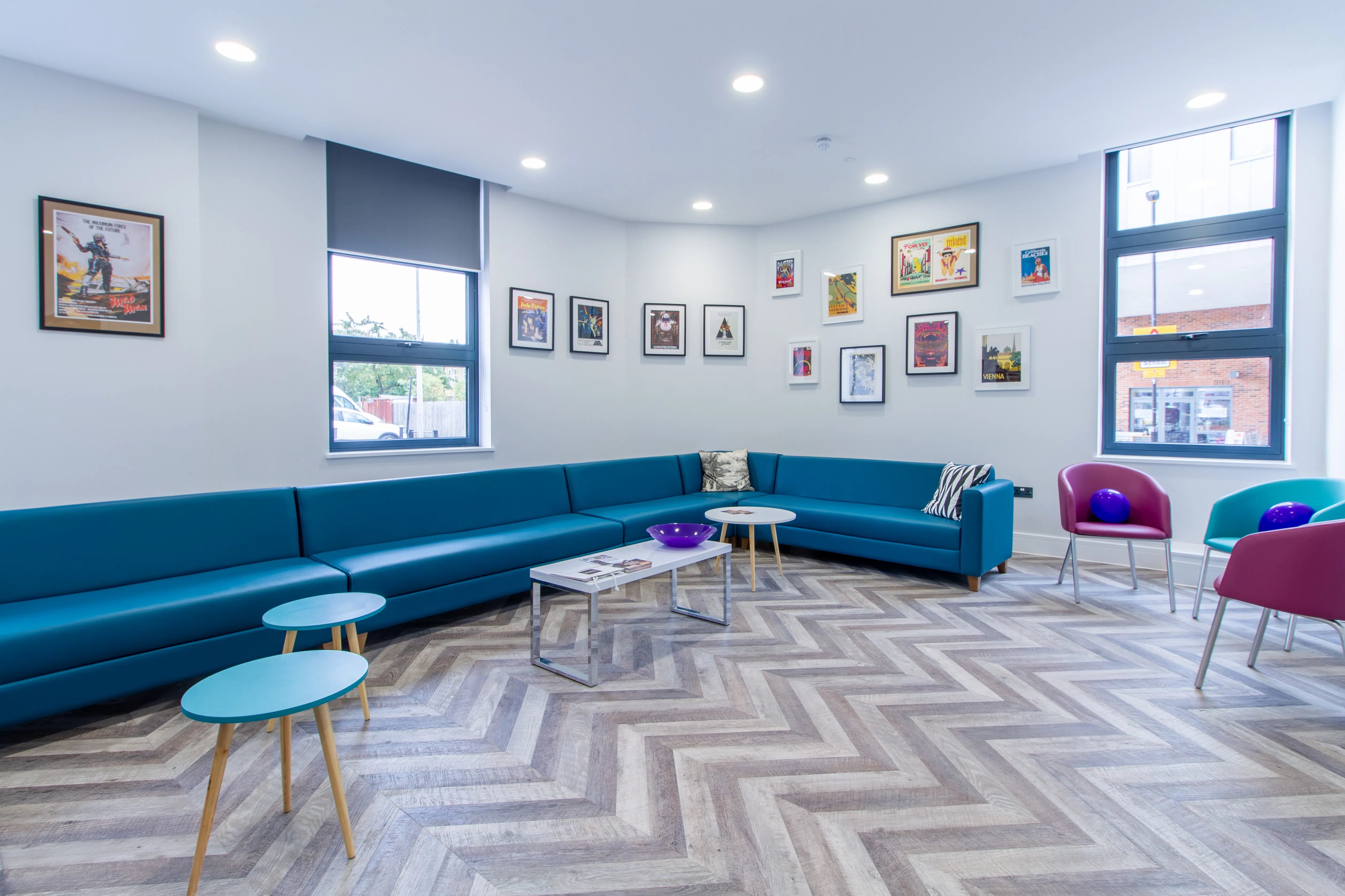 Blue sectional couch with colorful chairs living room at AXO Seven Sisters in London Student Accommodation