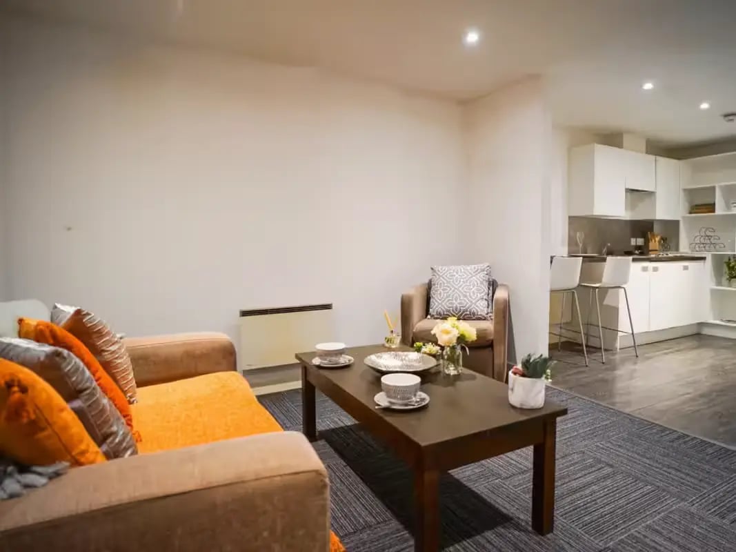 Sofa armchairs coffee table kitchen living room at Gallery Apartments in Glasgow Student Accommodation