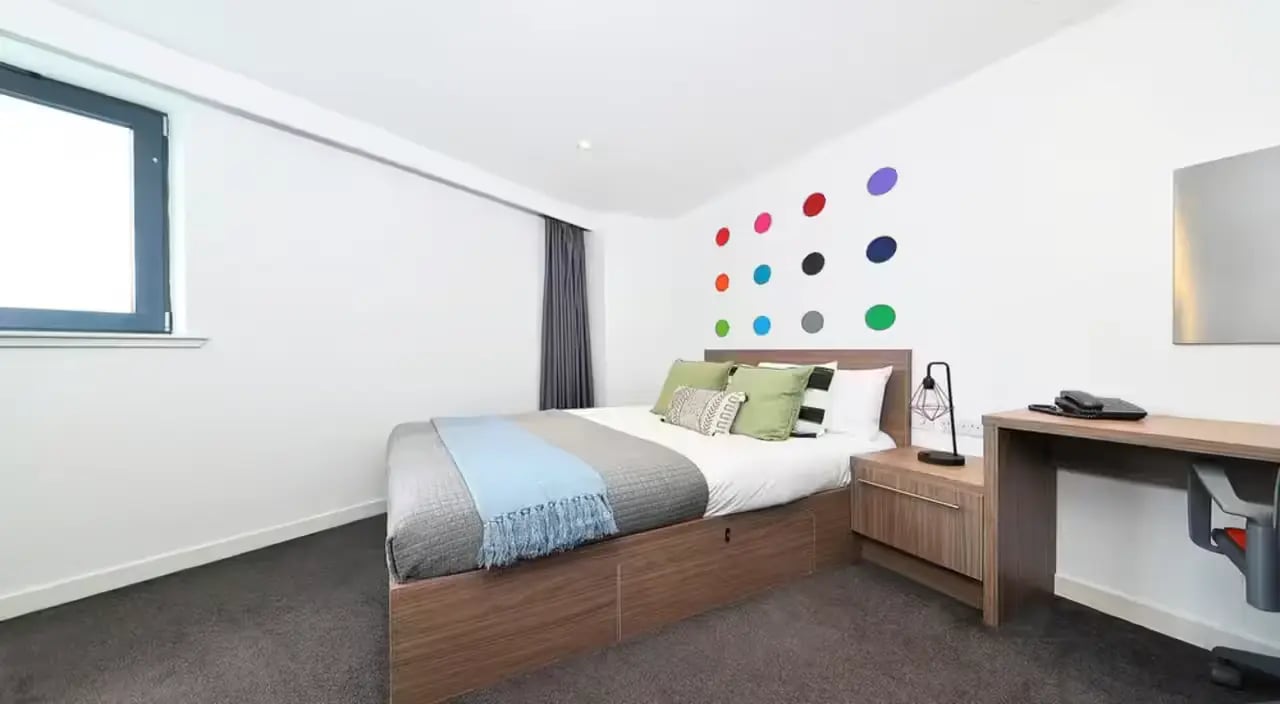 Bed pillows desk chair and wall art bedroom at Gallery Apartments in Glasgow Student Accommodation