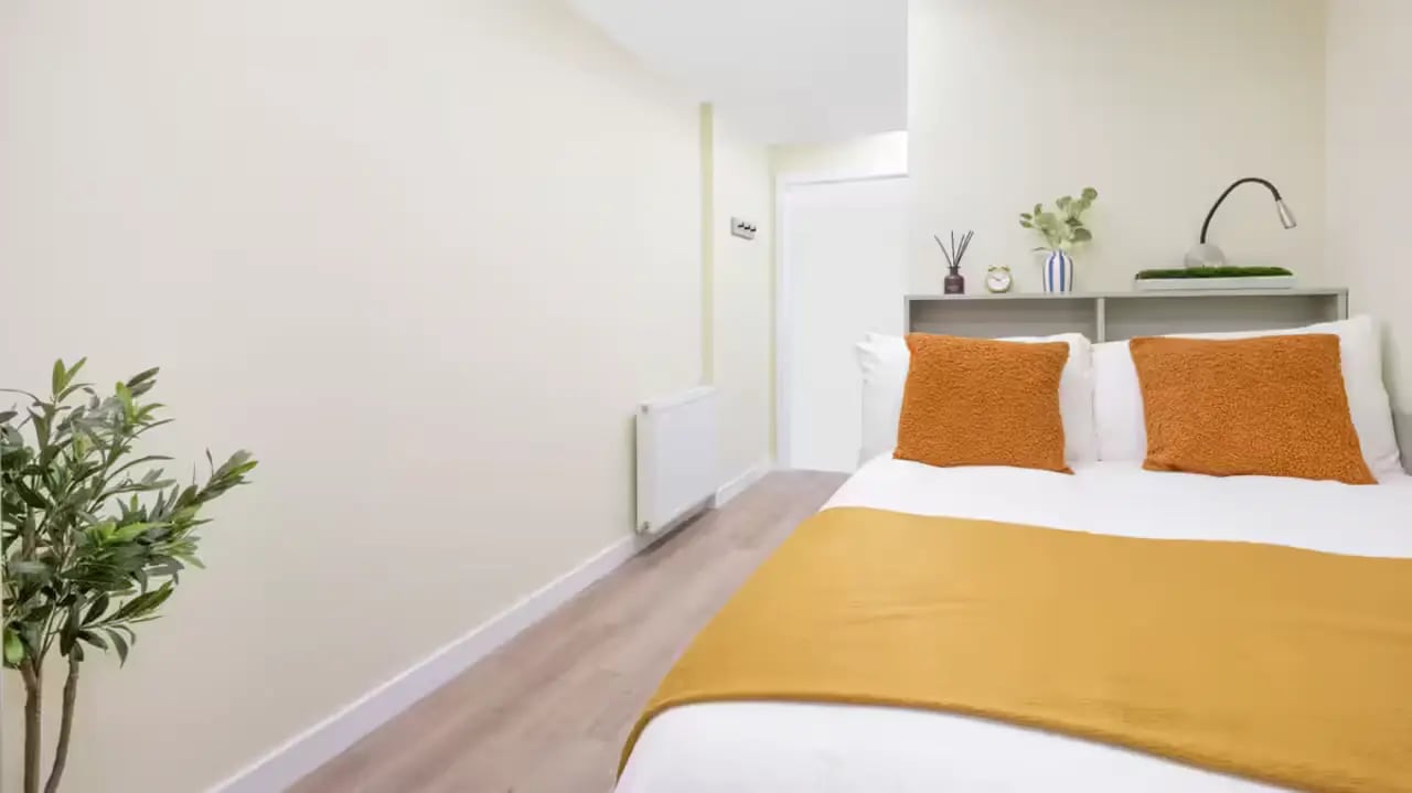 Bed with orange pillows and throw bedroom at St Vincent Studios in Glasgow Student Accommodation