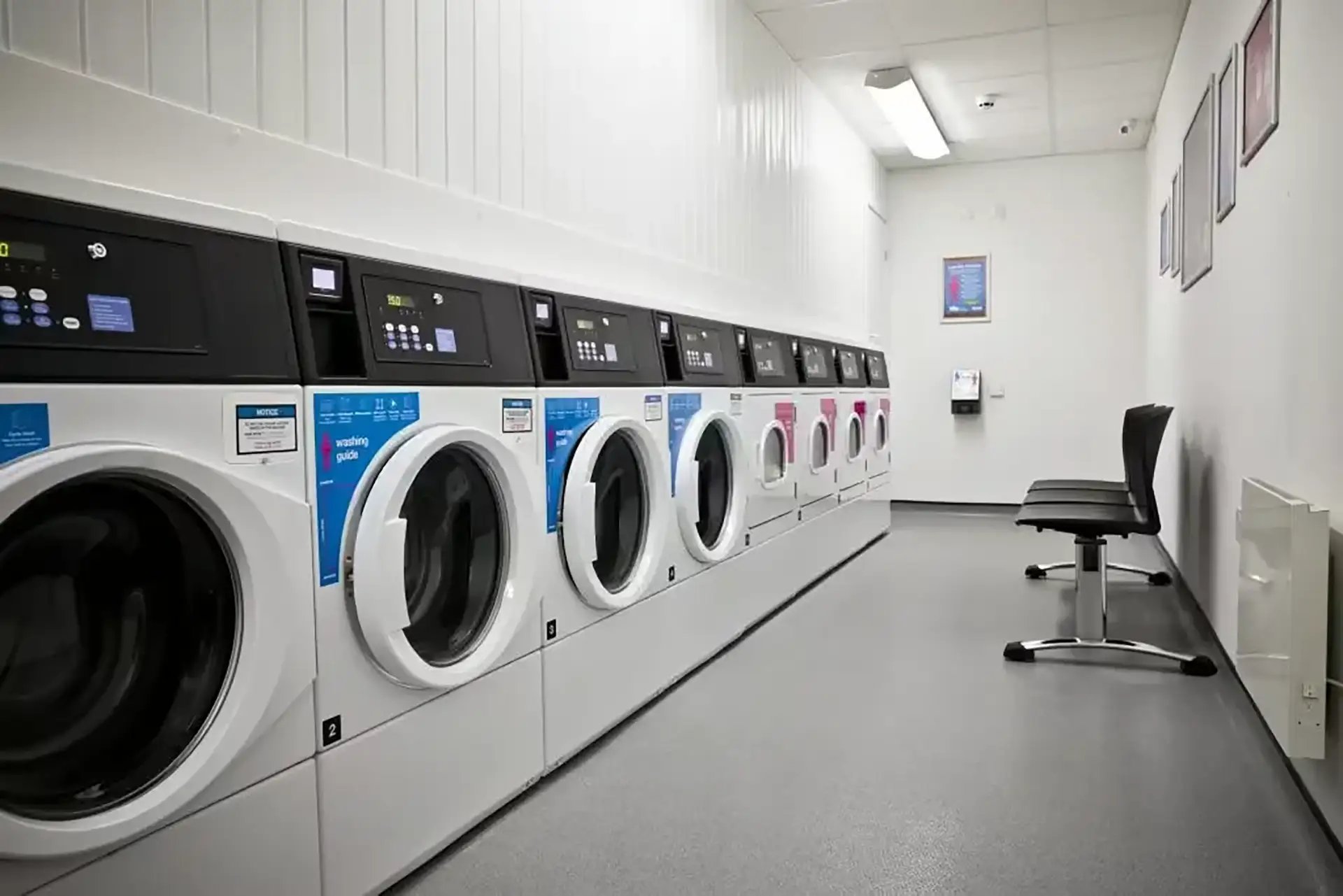 Row of washing machines with chairs laundry room at Friargate Court in Preston Student Accommodation
