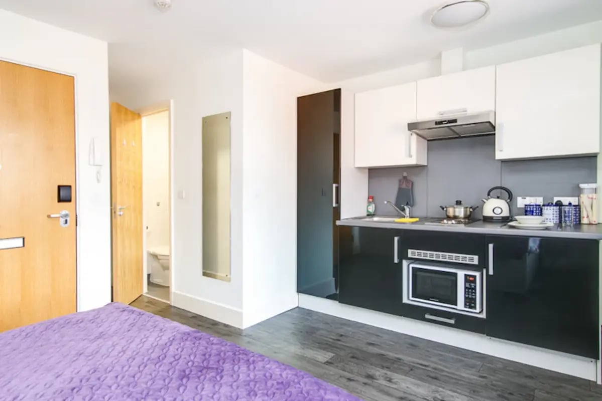 Purple bed, kitchen cabinets, microwave, sink kitchen at Ty Ni in Bangor Student Accommodation