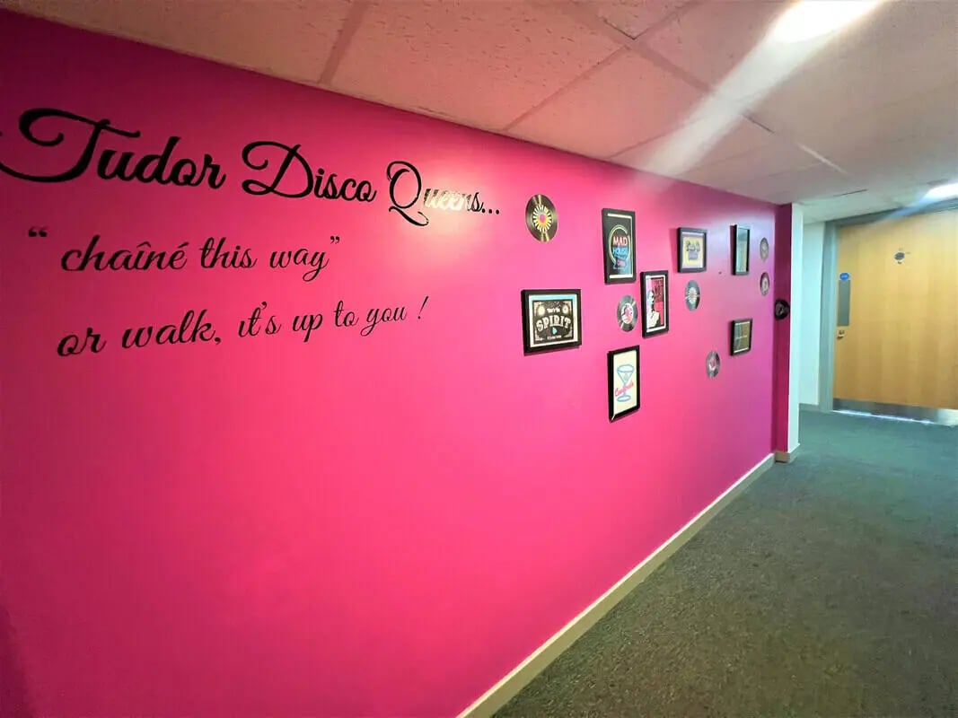 Pink wall with disco queens text and framed pictures Hallway at Tudor Studios in Leicester Student Accommodation