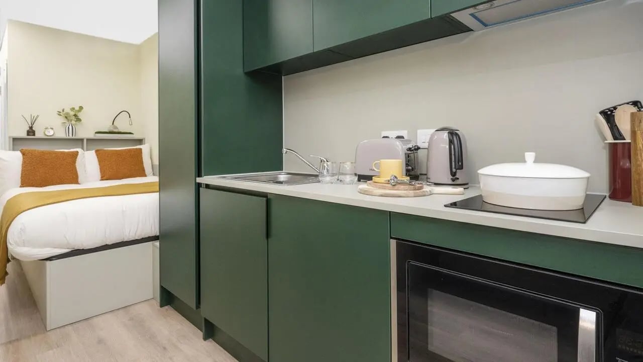 Bed and green kitchen with appliances kitchen at St Vincent Studios in Glasgow Student Accommodation