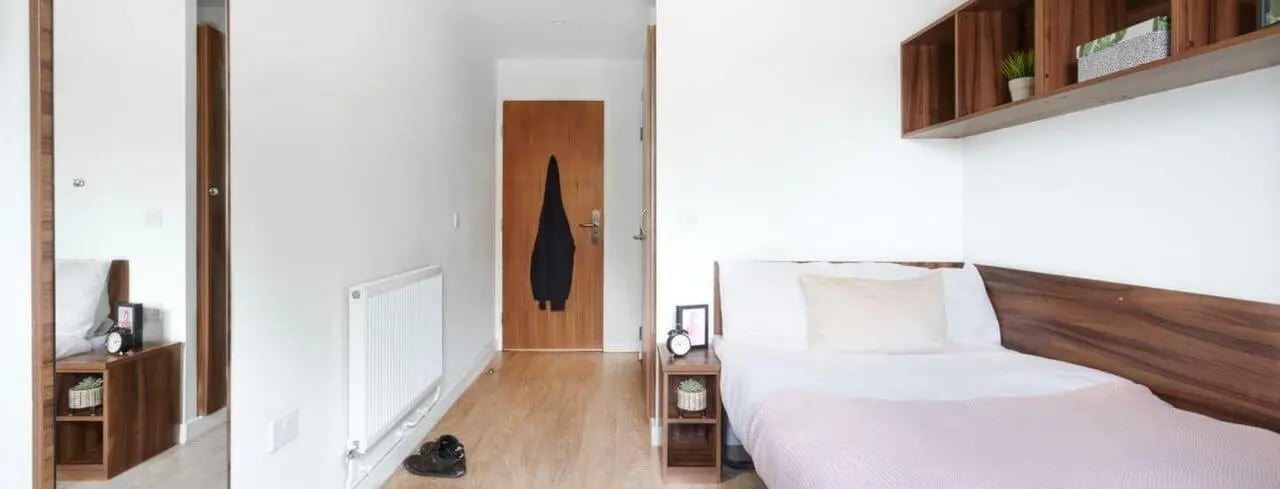 Bed clock plant wooden shelves doorway bedroom at The Printworks in Exeter Student Accommodation