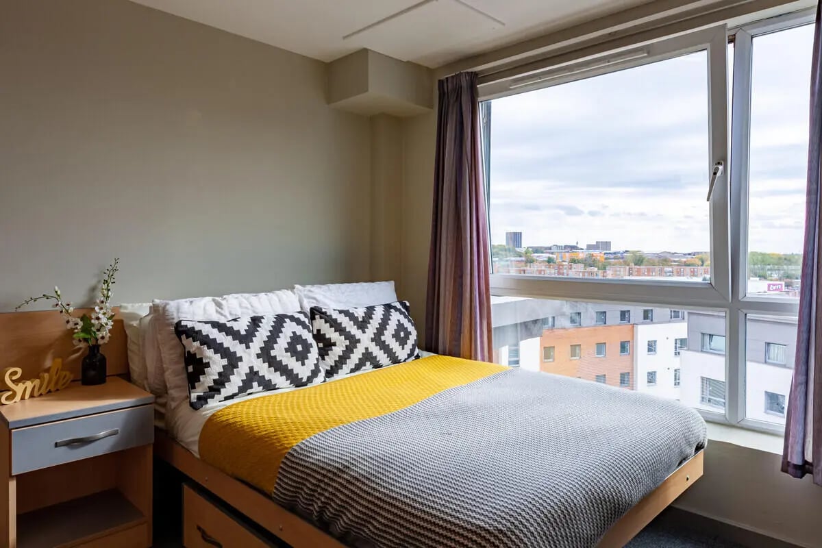 Bed with yellow and grey throws geometric pillows Bedroom at Filbert Village in Leicester Student Accommodation