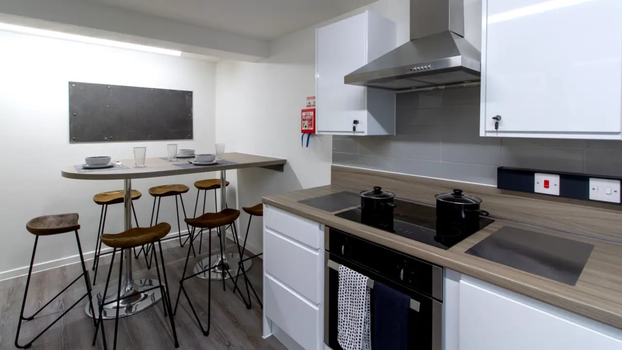 Table with stools and kitchen counter kitchen at Green Wood Court in Southampton Student Accommodation