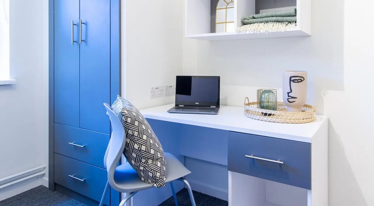 Blue wardrobe desk laptop chair pillow study area at Green Wood Court in Southampton Student Accommodation