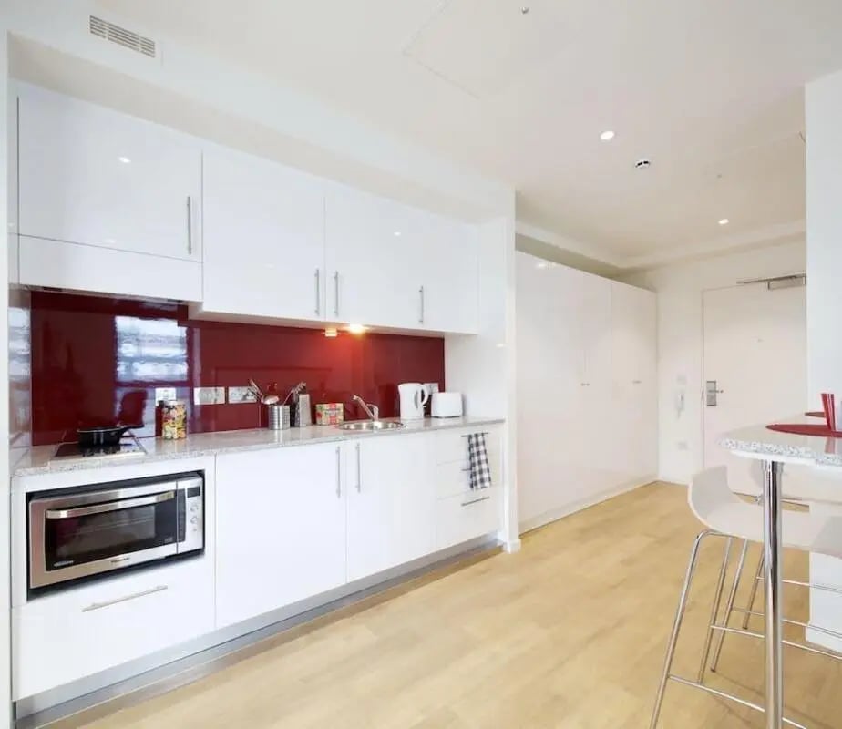 Modern white kitchen with red backsplash kitchen at Wood Lane Studios in London Student Accommodation