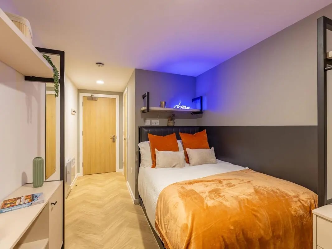 Bed with orange throws and pillows bedroom at Arcadian in Nottingham Student Accommodation