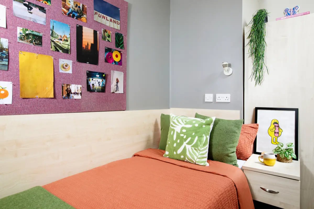 Bed with orange blanket green pillows artwork Bedroom at Newarke Point in Leicester Student Accommodation