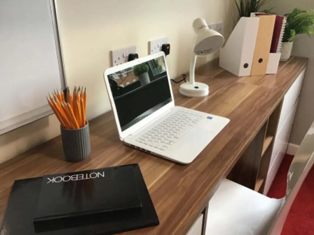 Desk with laptop lamp notebooks and pencils study area at Canterbury Student Village in Canterbury Student Accommodation