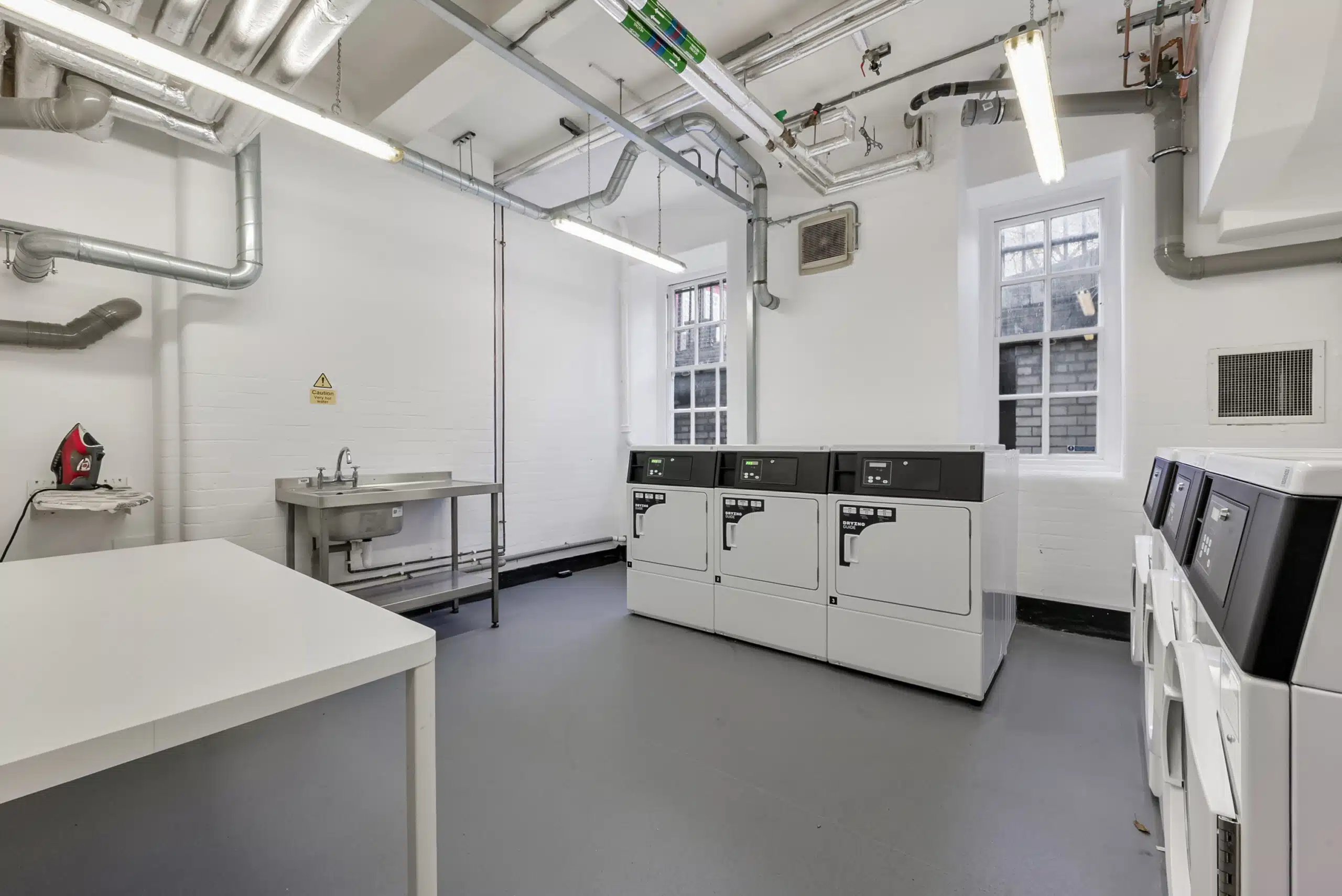 Washing machines sinks and folding table laundry room at AXO Waterloo in London Student Accommodation