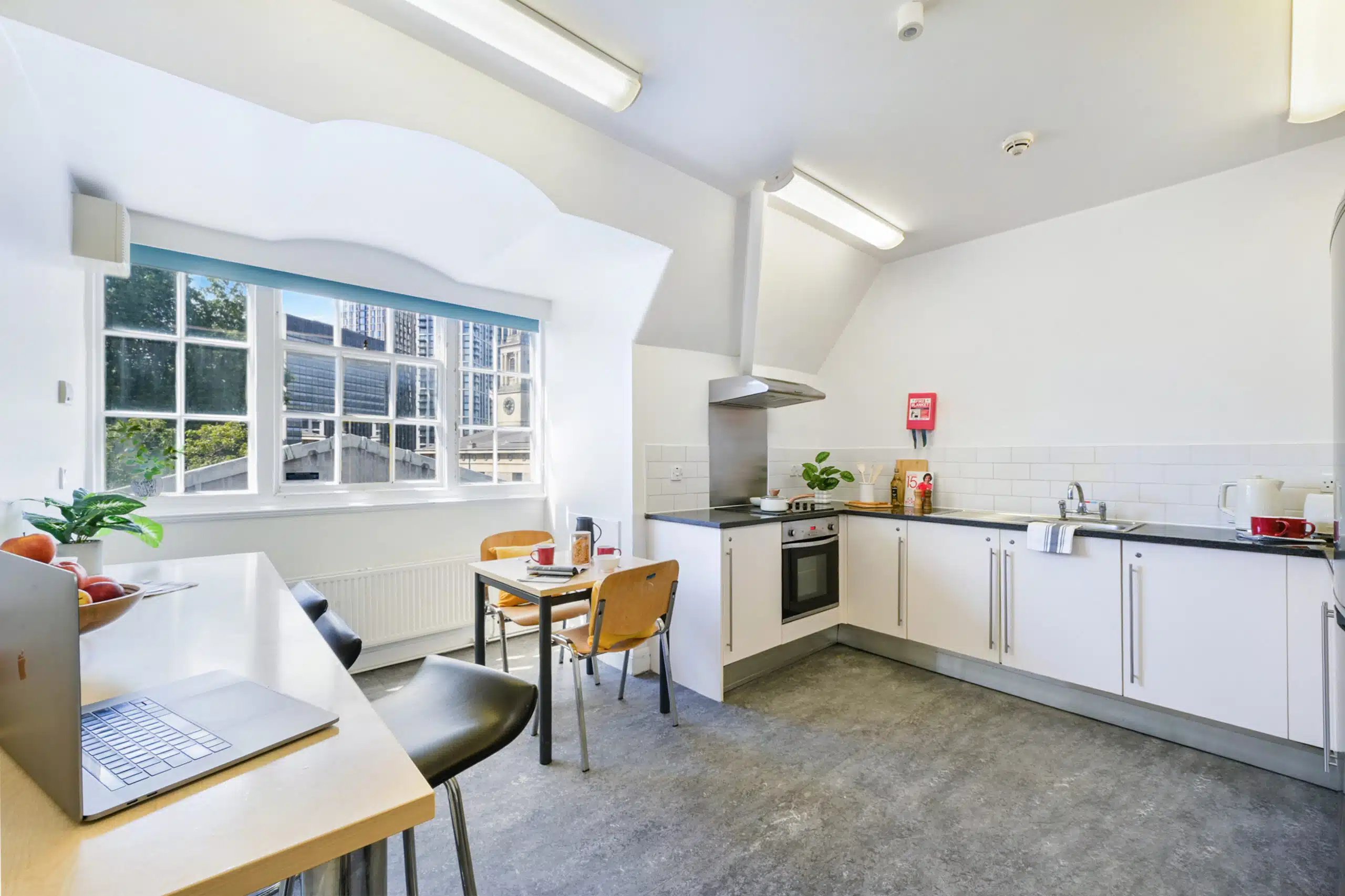 Laptop fruit bowl table chairs stove cabinets kitchen at AXO Waterloo in London Student Accommodation