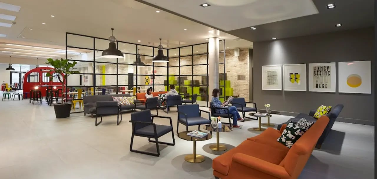 Modern lounge with red tube booth and artwork common area at Spring Mews in London Student Accommodation