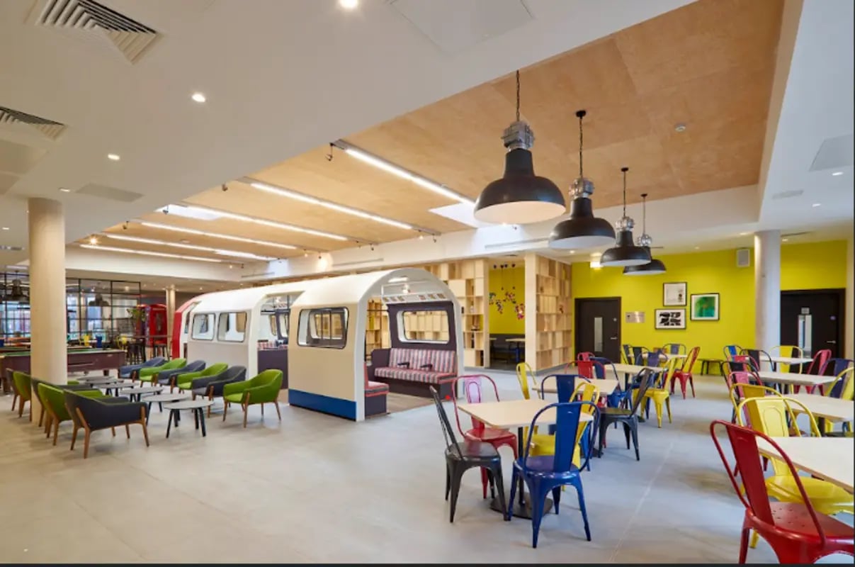 Student common area with subway car seating and tables at Spring Mews in London Student Accommodation