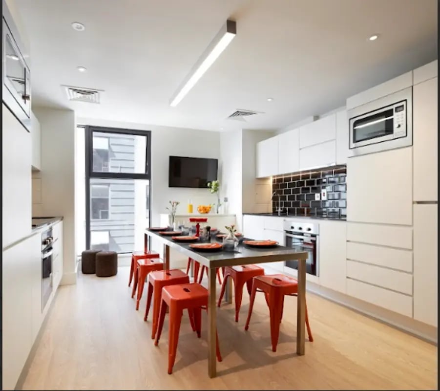 Kitchen with dining table and orange stools kitchen at Spring Mews in London Student Accommodation