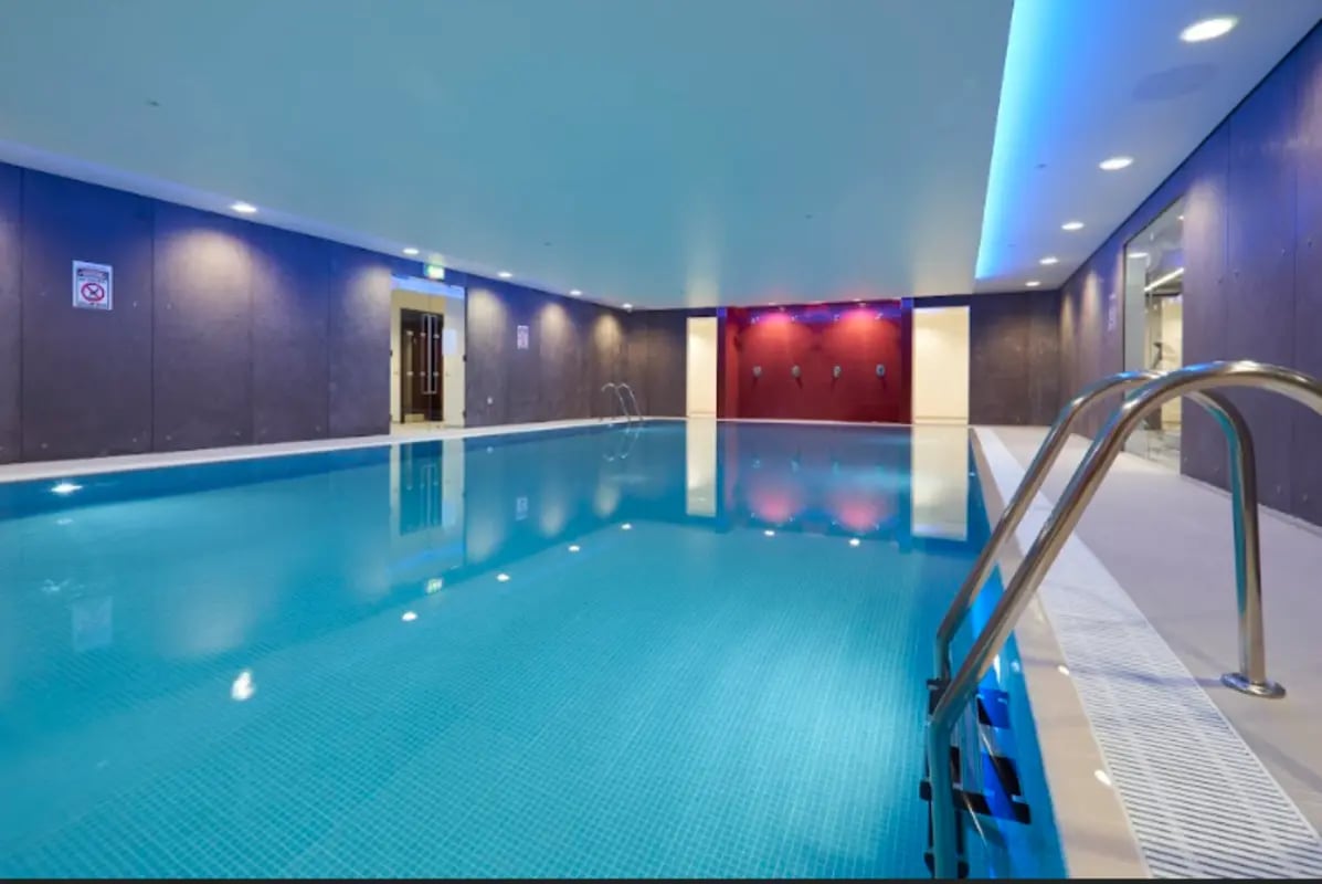 Indoor swimming pool with blue lights and steps at Spring Mews in London Student Accommodation