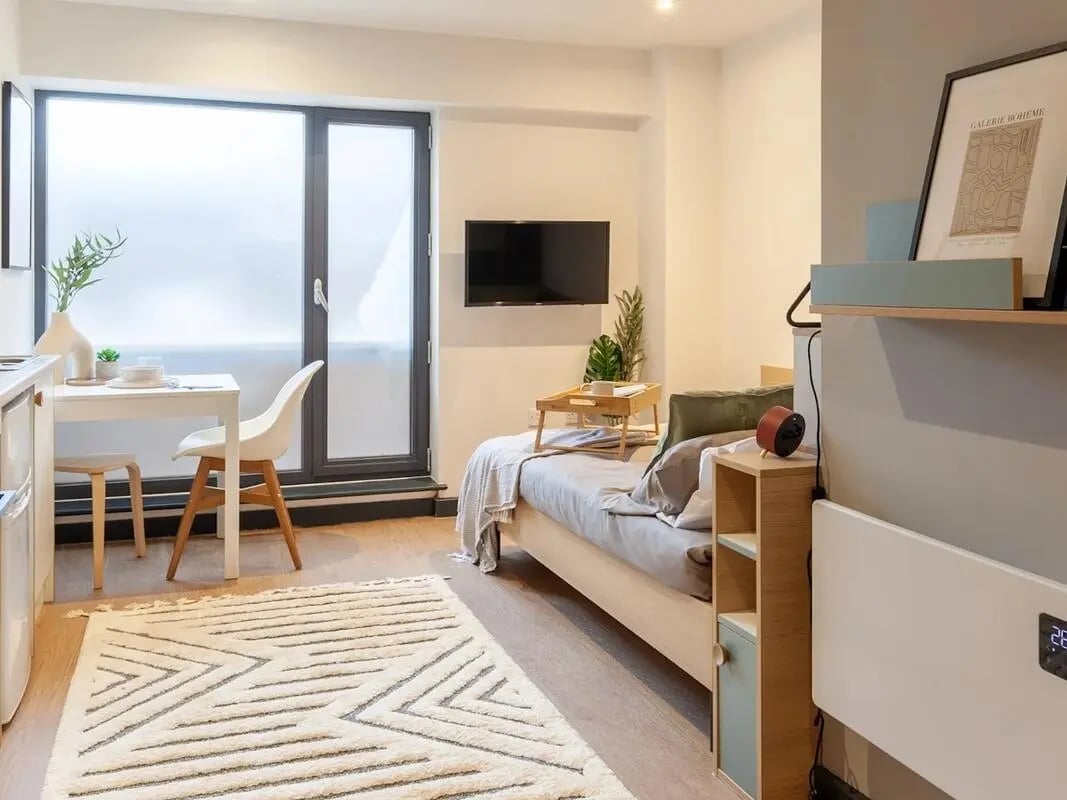 Bed with tray desk chairs and rug bedroom at The Gorge in Exeter Student Accommodation
