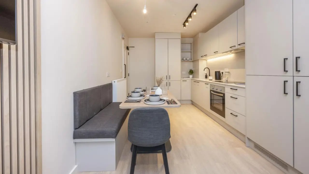 Table with seating and kitchen cabinets kitchen at Press House in London Student Accommodation