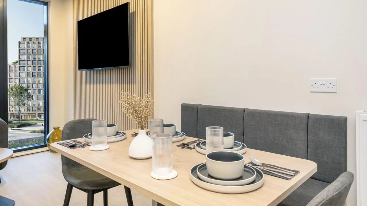 Dining table with place settings and banquette seating Living room at Press House in London Student Accommodation