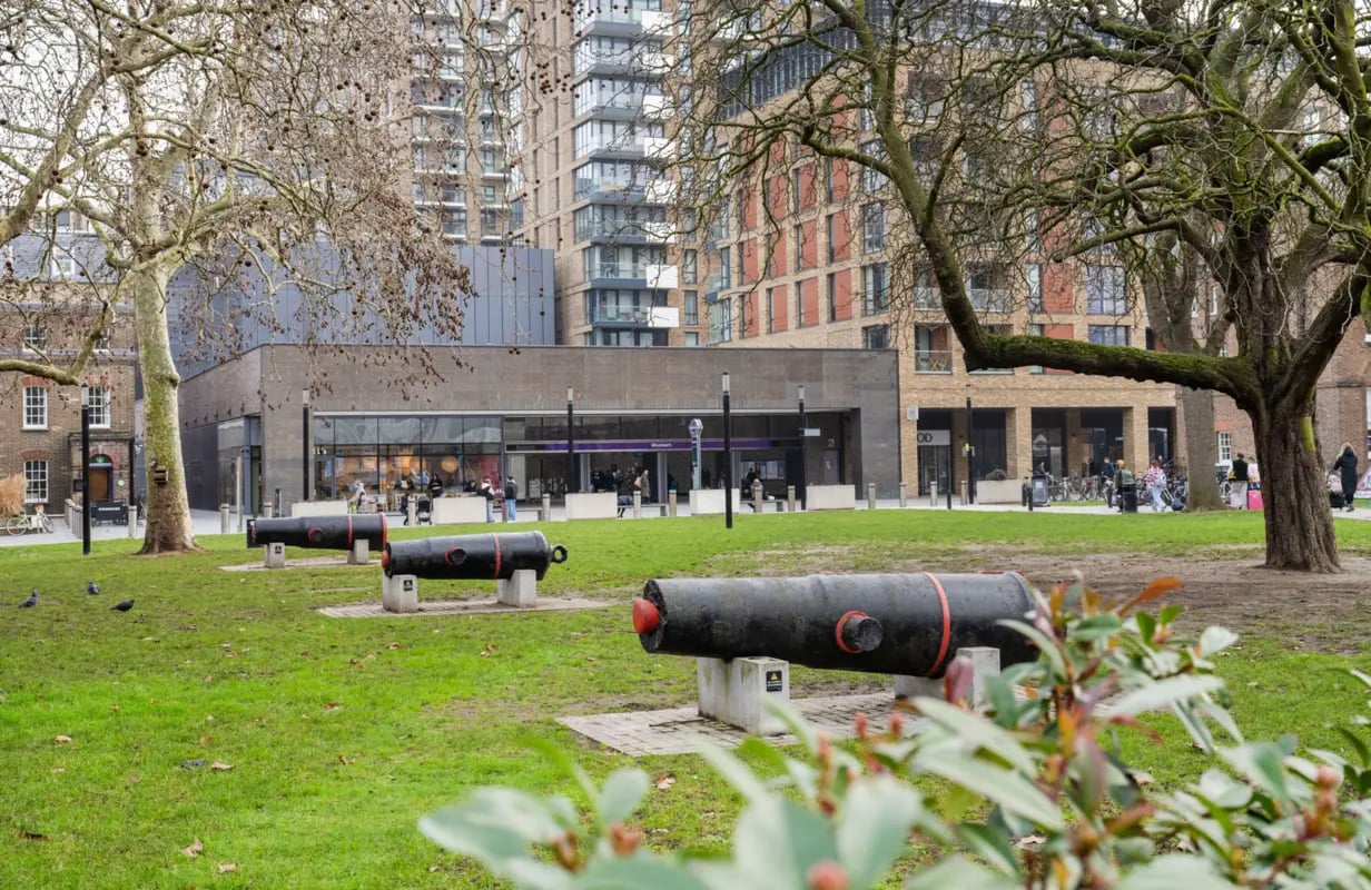 Cannons on grass with modern buildings exterior at Press House in London Student Accommodation