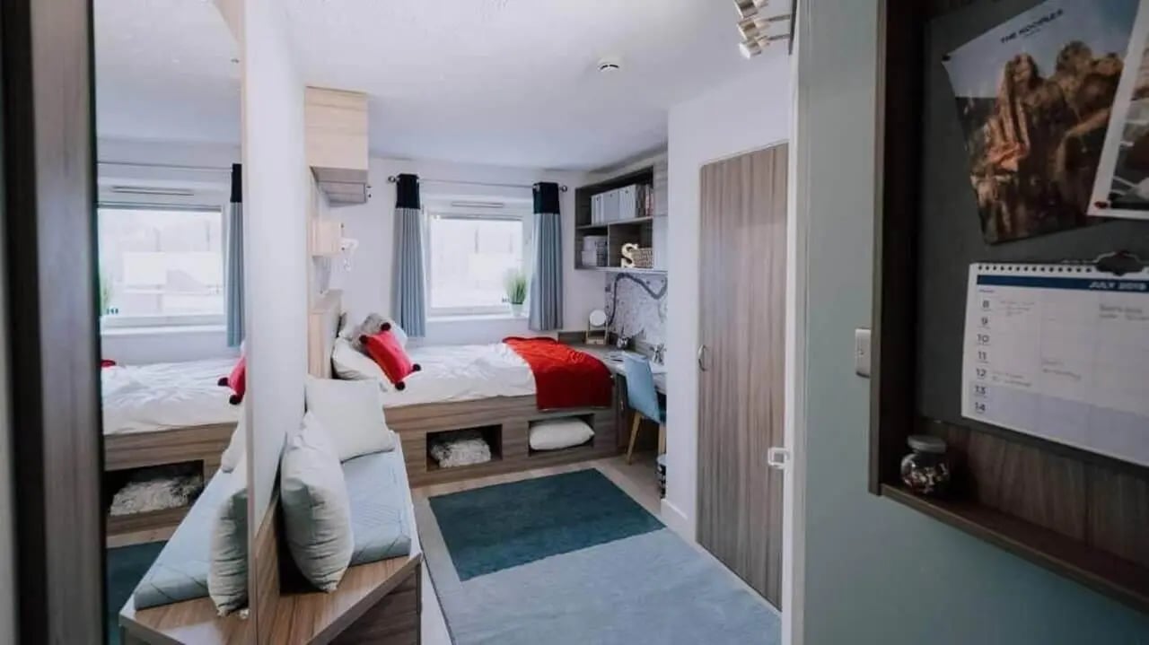 Two beds red throw pillows study area bedroom at Manna Ash House in London Student Accommodation