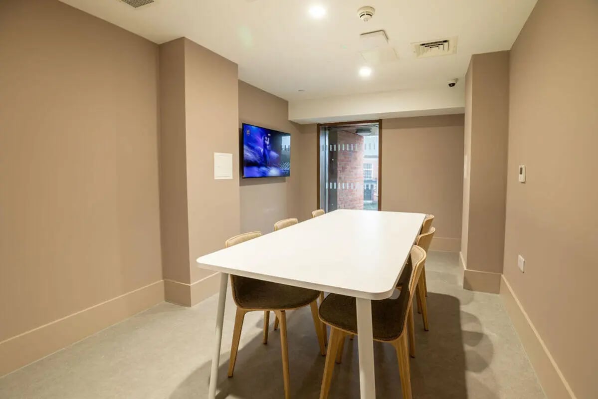 White table and chairs with wall mounted television common room at Yugo Crown Place in Birmingham Student Accommodation