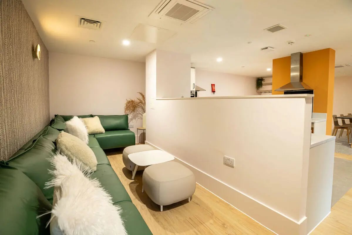 Green sectional sofa with ottomans and coffee table common area at Yugo Crown Place in Birmingham Student Accommodation