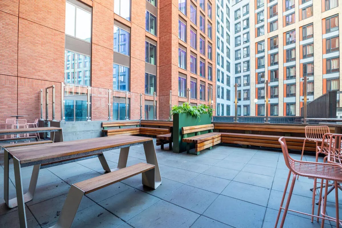 Outdoor seating area with picnic tables and benches exterior at Yugo Crown Place in Birmingham Student Accommodation