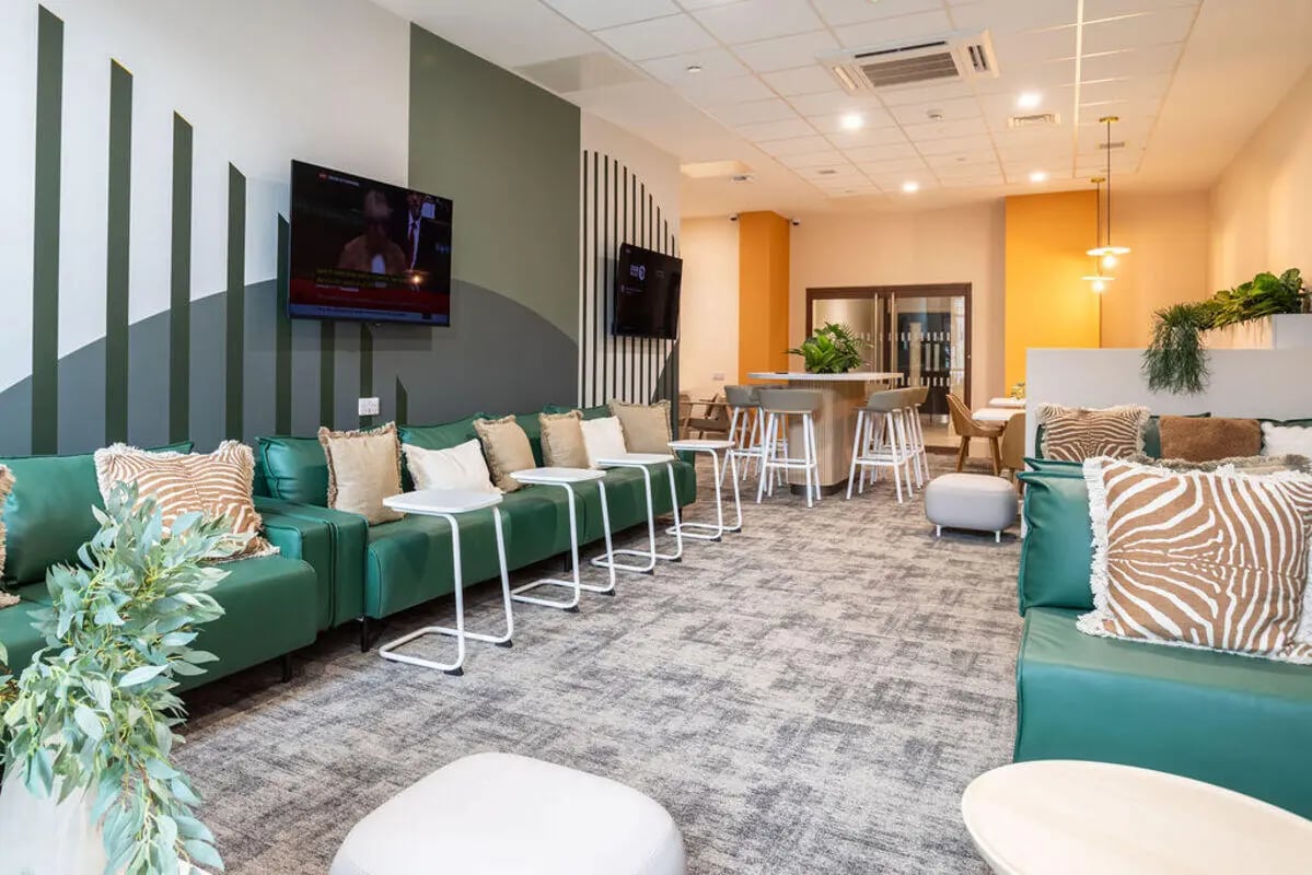 Green sofas with patterned pillows and small tables living room at Yugo Crown Place in Birmingham Student Accommodation