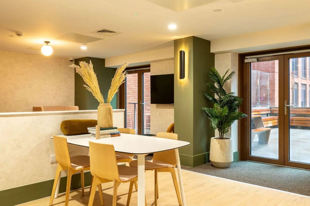 Dining table chairs plant and TV communal area at Yugo Crown Place in Birmingham Student Accommodation