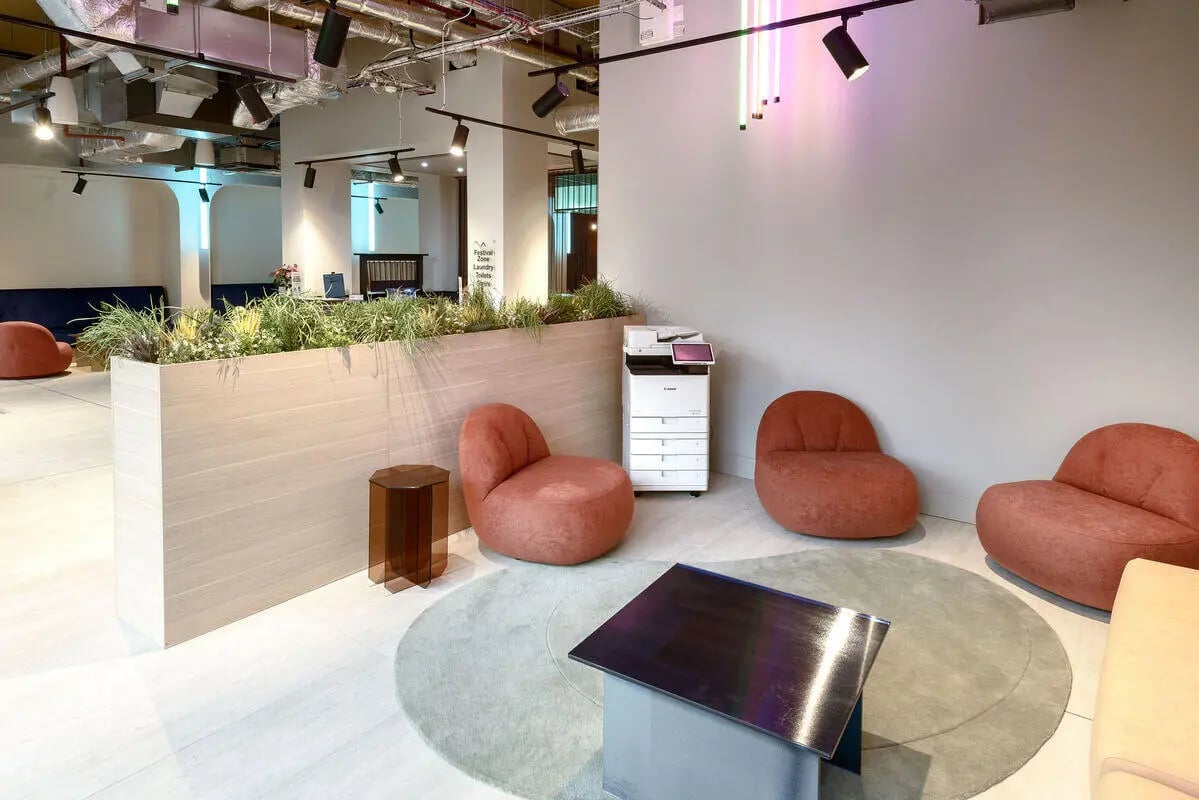 Coral chairs printer plant divider lounge area at True Nottingham in Nottingham Student Accommodation