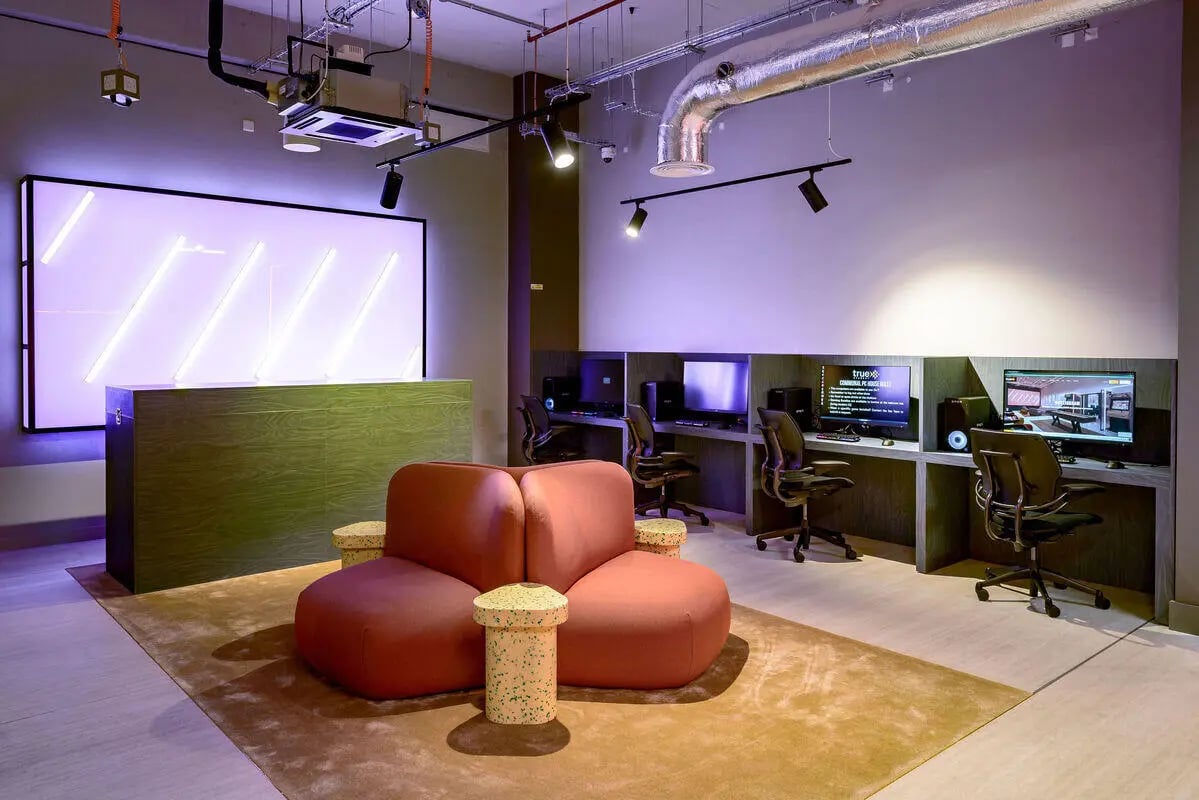 Lounge area with gaming stations and reception desk playing area at True Nottingham in Nottingham Student Accommodation