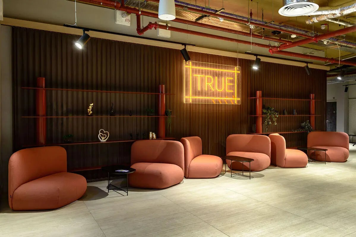 Orange armchairs neon sign shelving living room at True Nottingham in Nottingham Student Accommodation