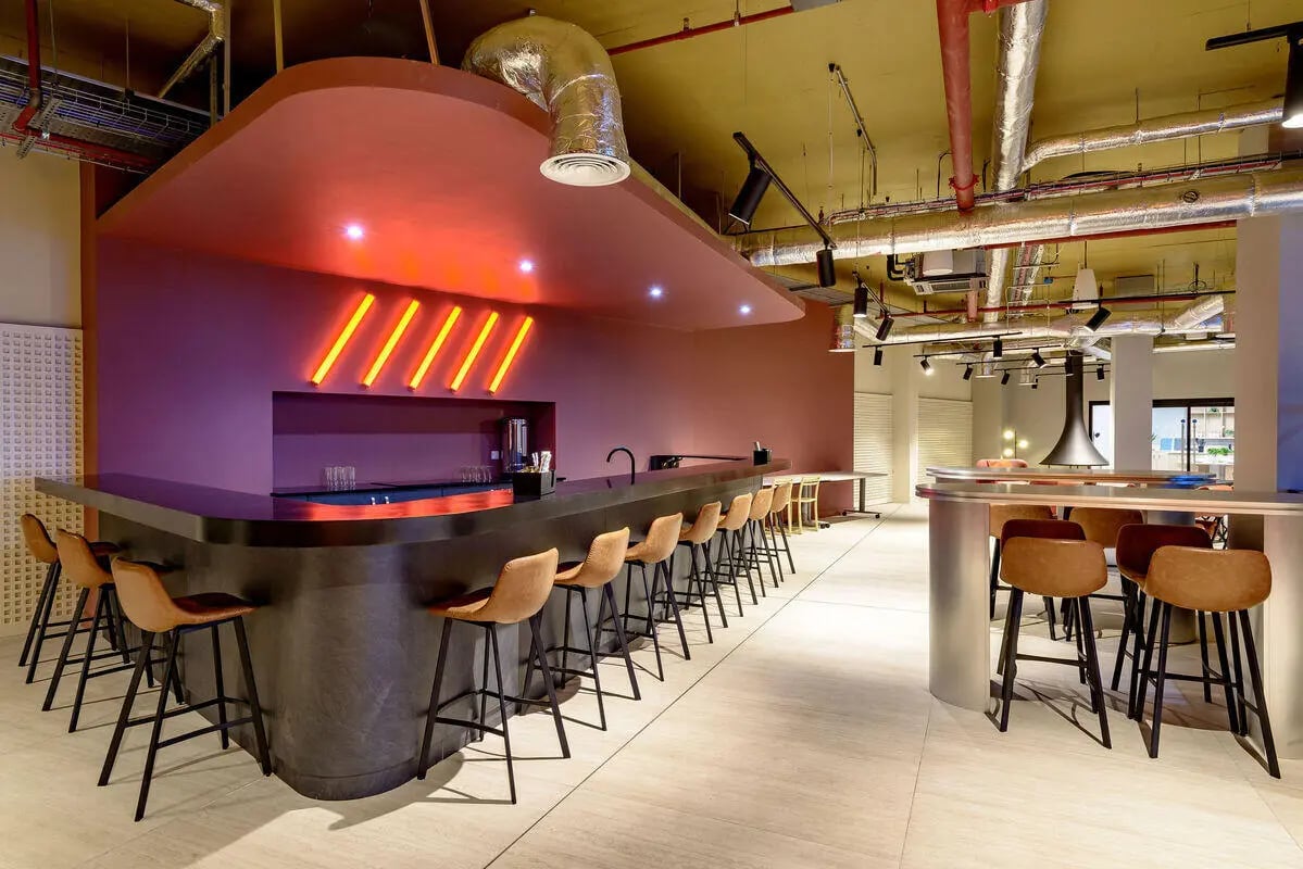 Bar with stools neon lights and ductwork common area at True Nottingham in Nottingham Student Accommodation