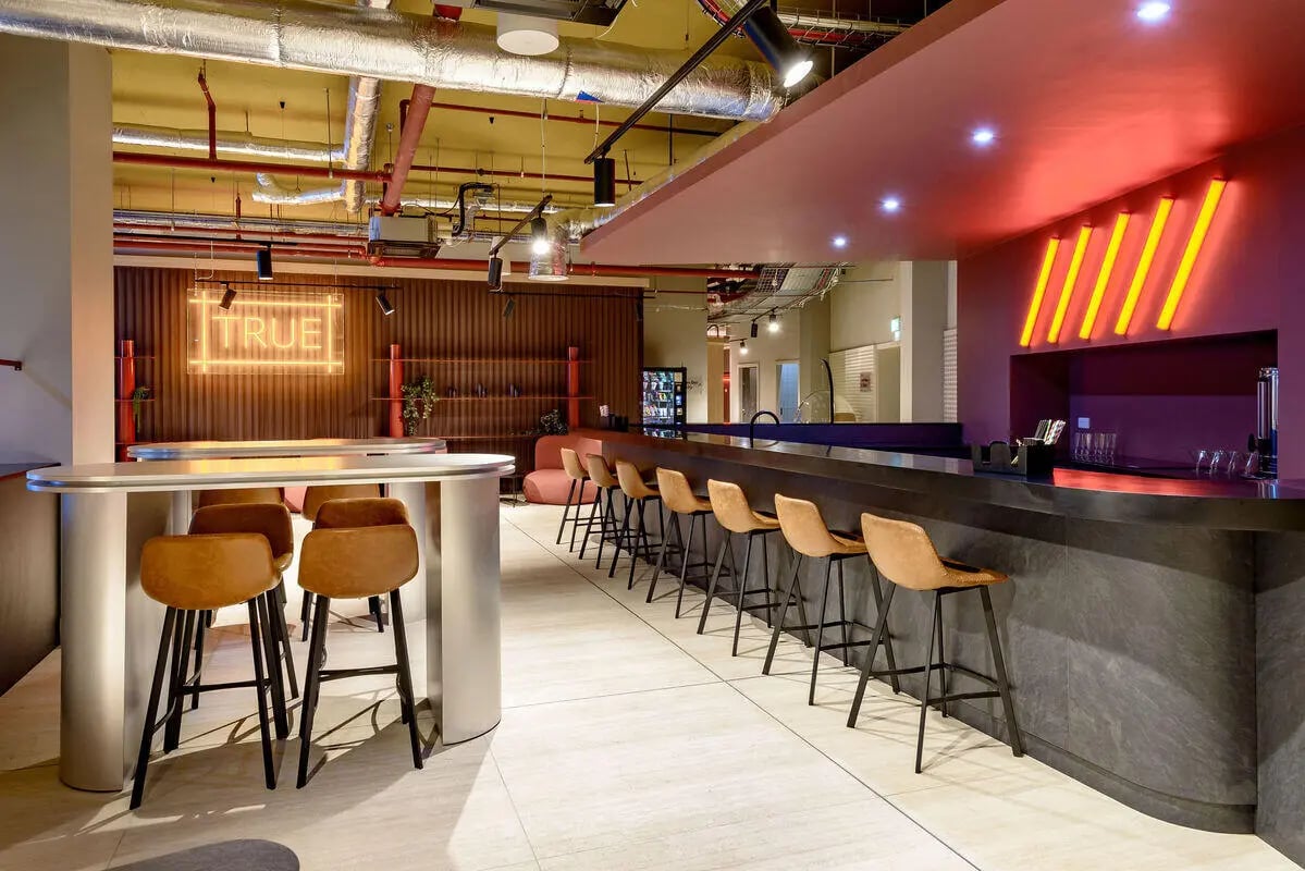 Bar with counter seating and neon sign communal area at True Nottingham in Nottingham Student Accommodation