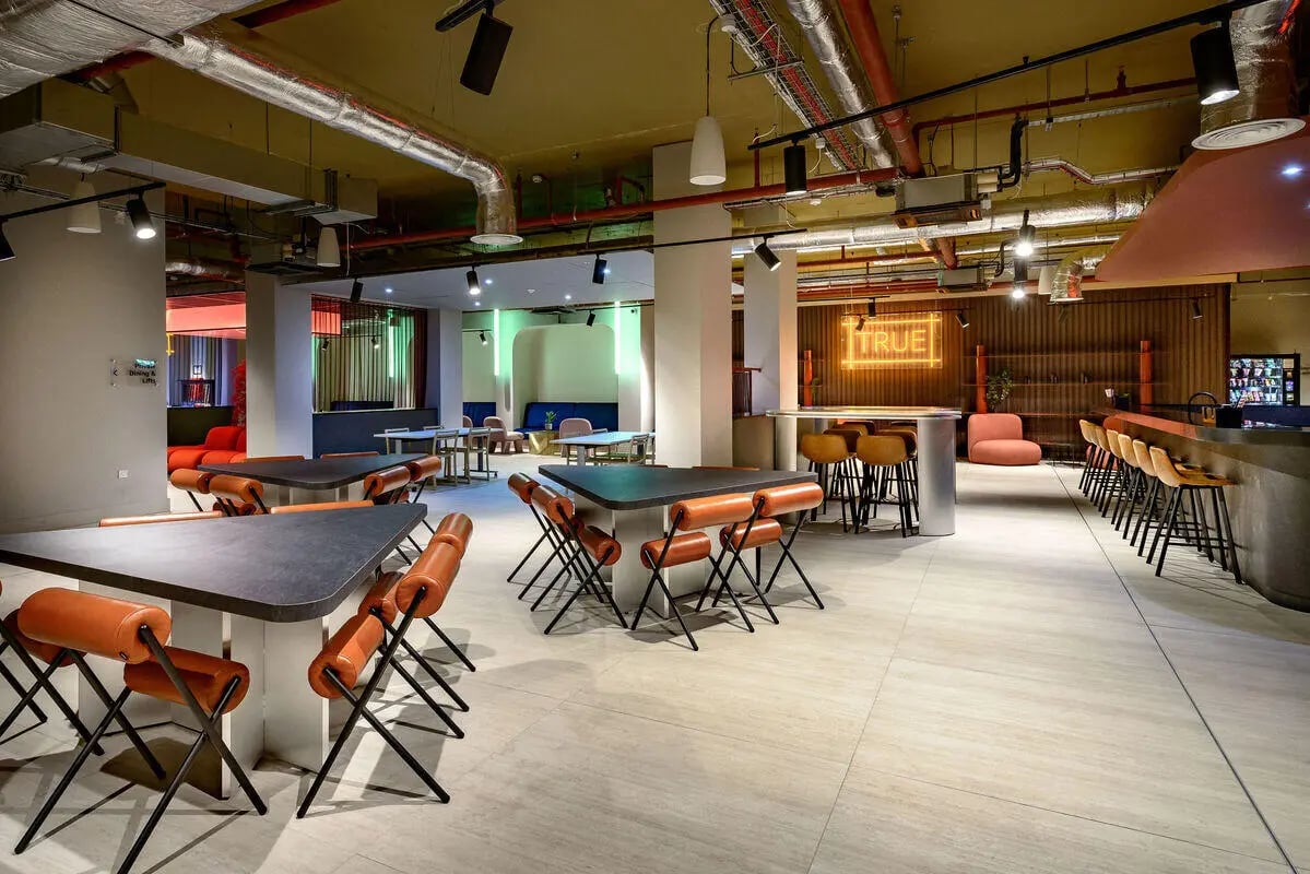 Student accommodation common area with tables chairs and bar at True Nottingham in Nottingham Student Accommodation