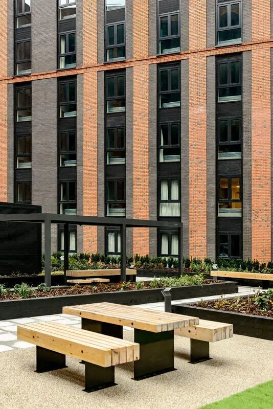 Wooden picnic tables and benches exterior at True Nottingham in Nottingham Student Accommodation