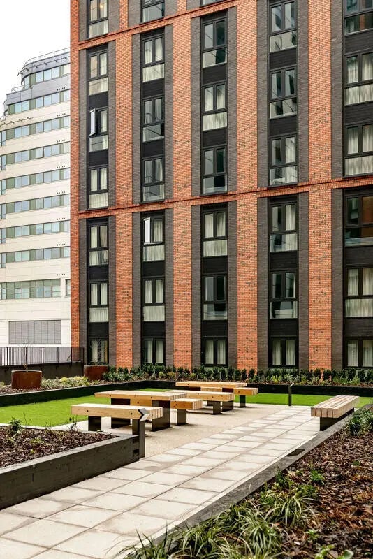 Wooden benches and tables on patio exterior at True Nottingham in Nottingham Student Accommodation