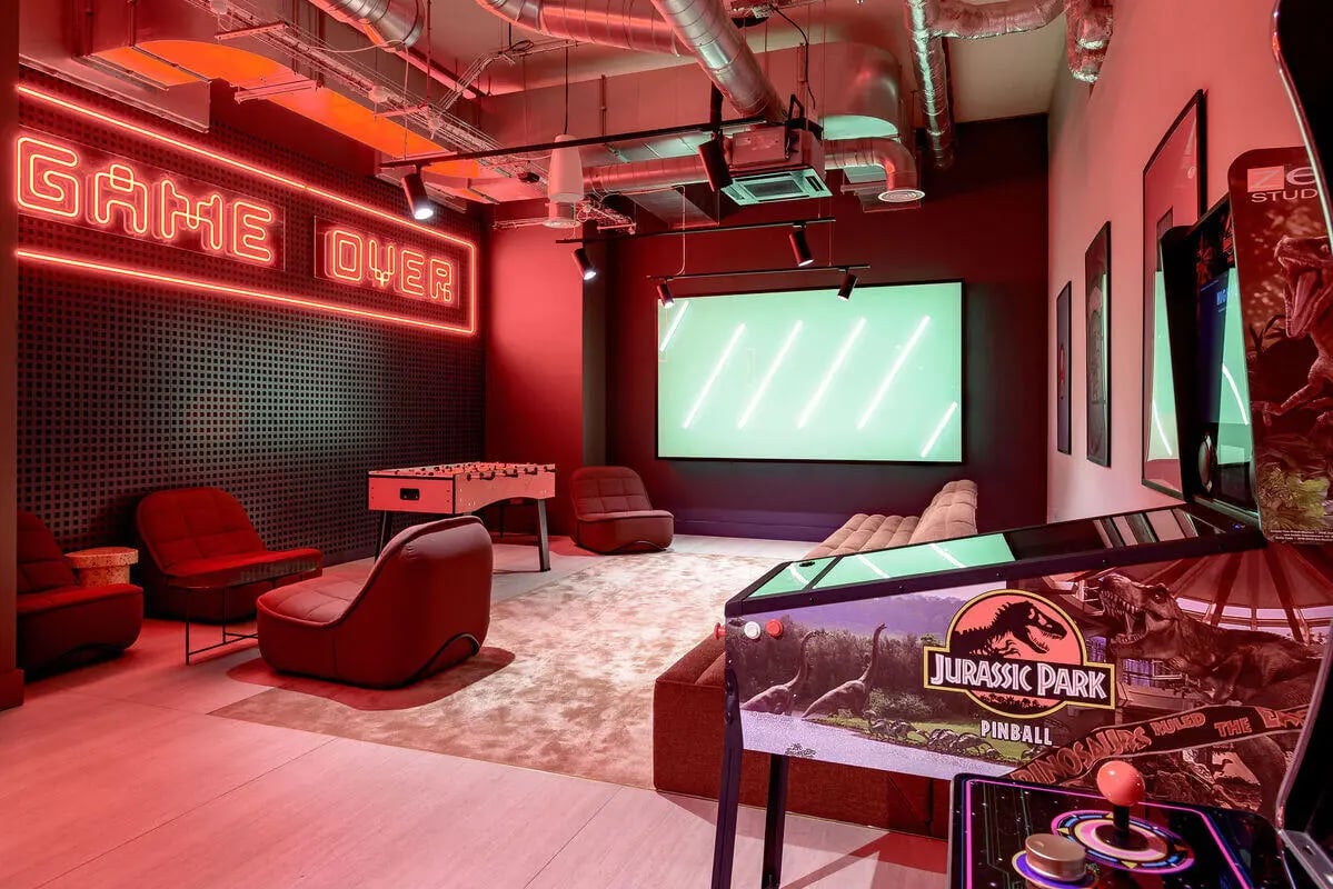 Neon signs chairs foosball Jurassic Park pinball playing area at True Nottingham in Nottingham Student Accommodation