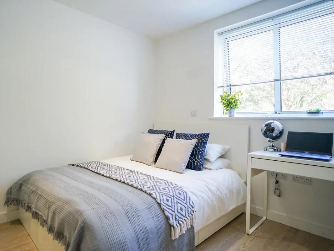 Bed with blue pillows and patterned throw Study desk Bedroom at Orme House in Newcastle Under Lyme Student Accommodation