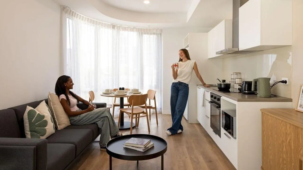 Sofa dining table kitchen with two women living room kitchen at UniLodge Perth Central in Perth Student Accommodation