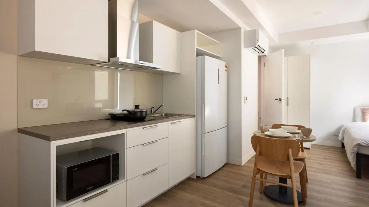 Kitchen with microwave fridge table chairs and bed. at UniLodge Perth Central in Perth Student Accommodation