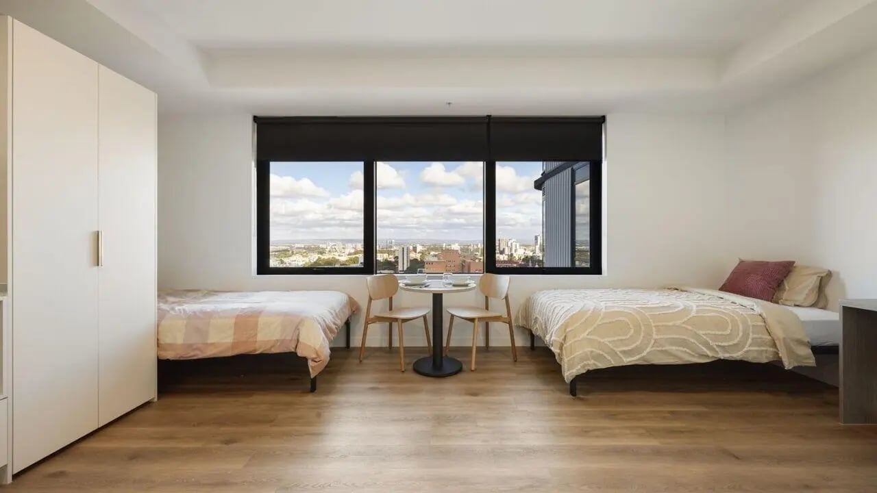 Two beds wardrobe table chairs bedroom at UniLodge Perth Central in Perth Student Accommodation