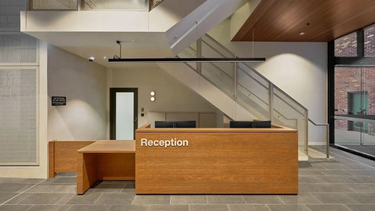 Wooden reception desk with computers and staircase reception area at UniLodge Perth Central in Perth Student Accommodation