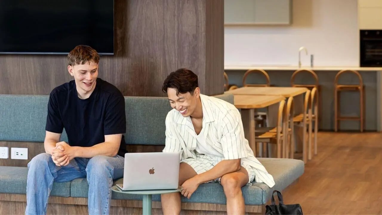 Two men laptop couch kitchen dining area common room at UniLodge Perth Central in Perth Student Accommodation